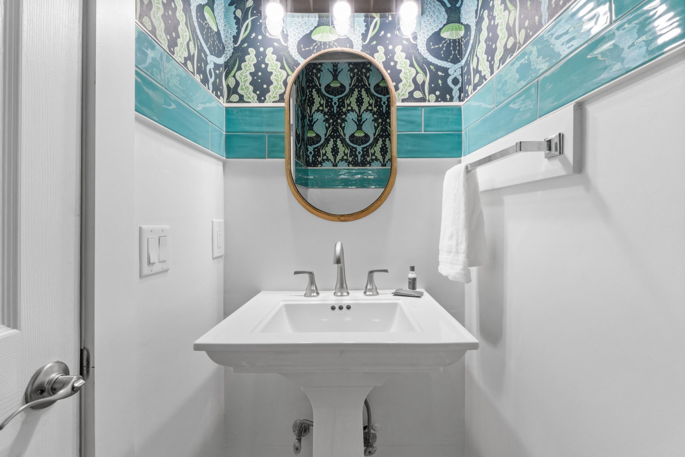 Een badkamer met een witte wastafel, twee kranen, een spiegel en een handdoekhouder.