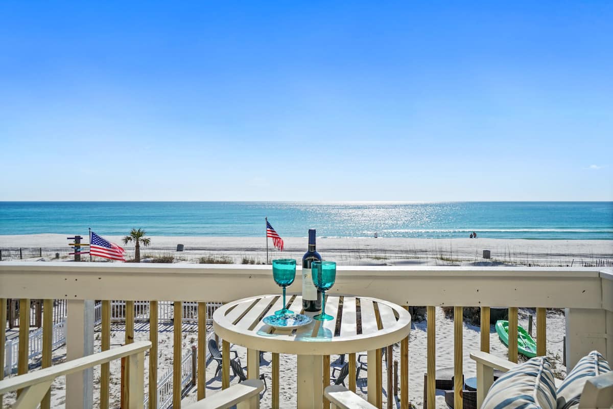 Ein Balkon mit Blick auf den Strand, zwei Gläser und eine amerikanische Flagge.
