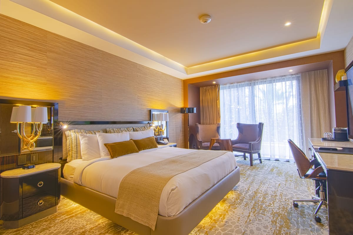 Een hotelkamer met een groot bed, nachtkastjes, een bureau en een stoel.