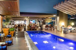 Zona de piscina interior con asientos y un bar al fondo.