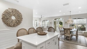 A modern kitchen with a central island, white cabinetry, and a decorative wall piece. - Villas of Seacrest Beach on 30A by Panhandle Getaways (Panama City Beach)