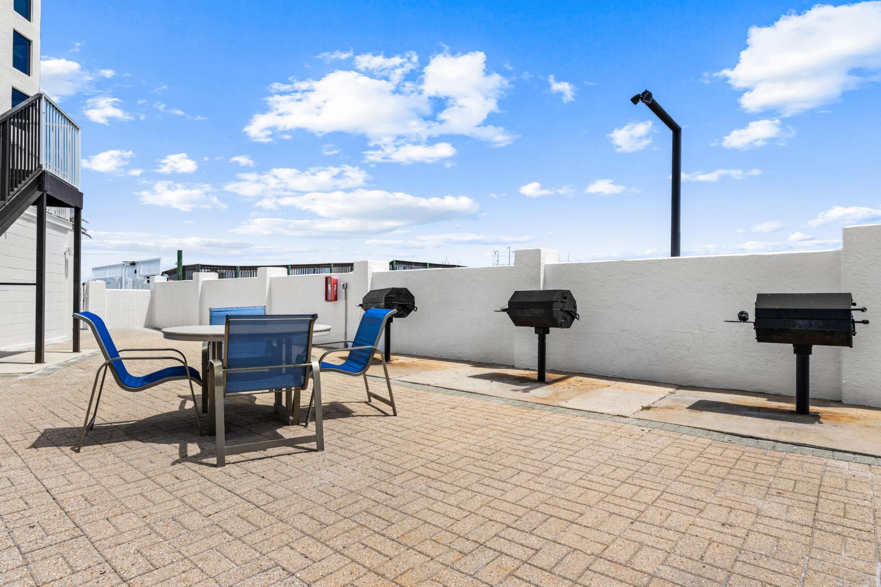 Une terrasse extérieure avec une table et des chaises, un barbecue et une poubelle.