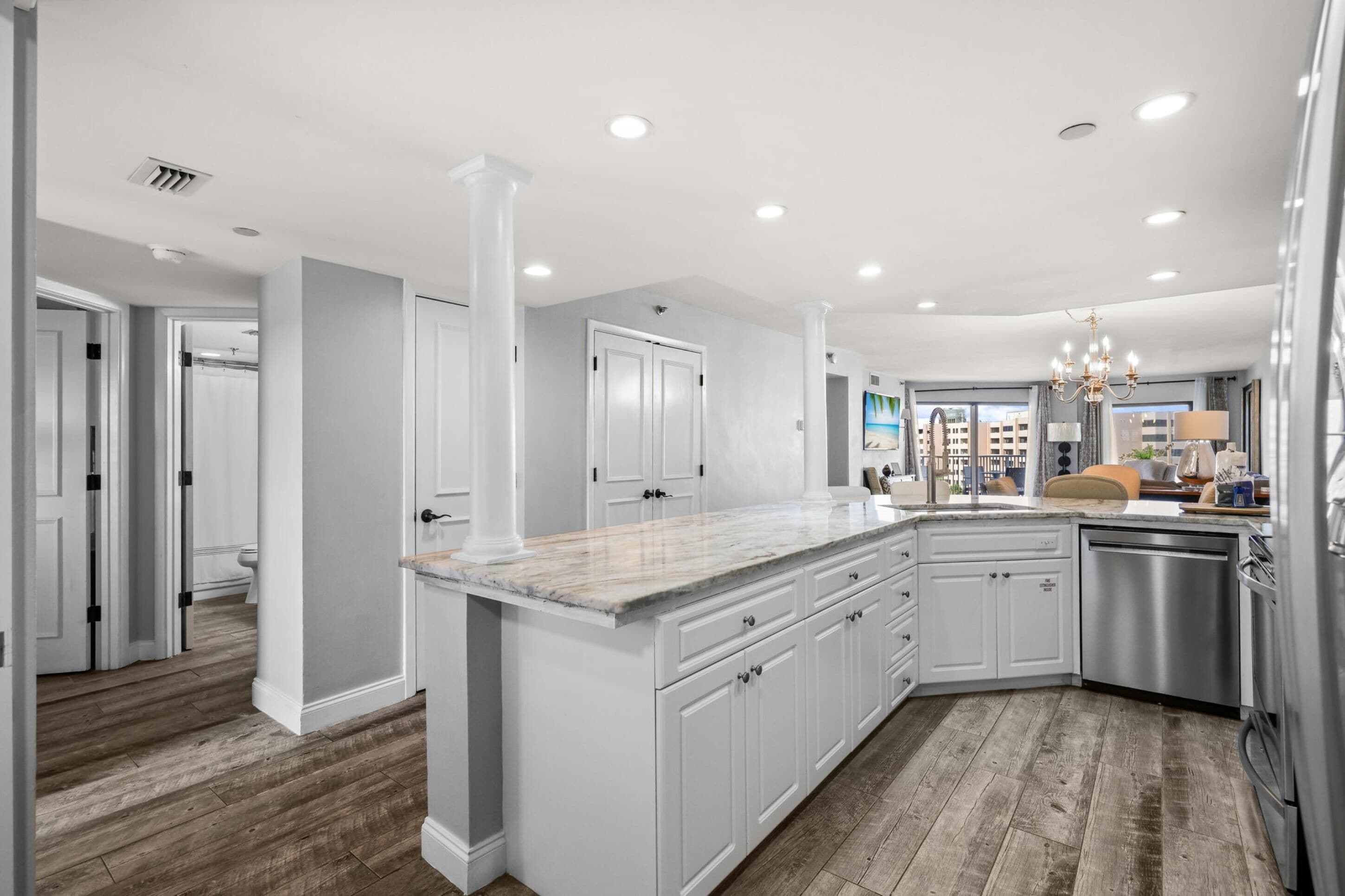 A modern kitchen with white cabinetry, a marble countertop, and stainless steel appliances.