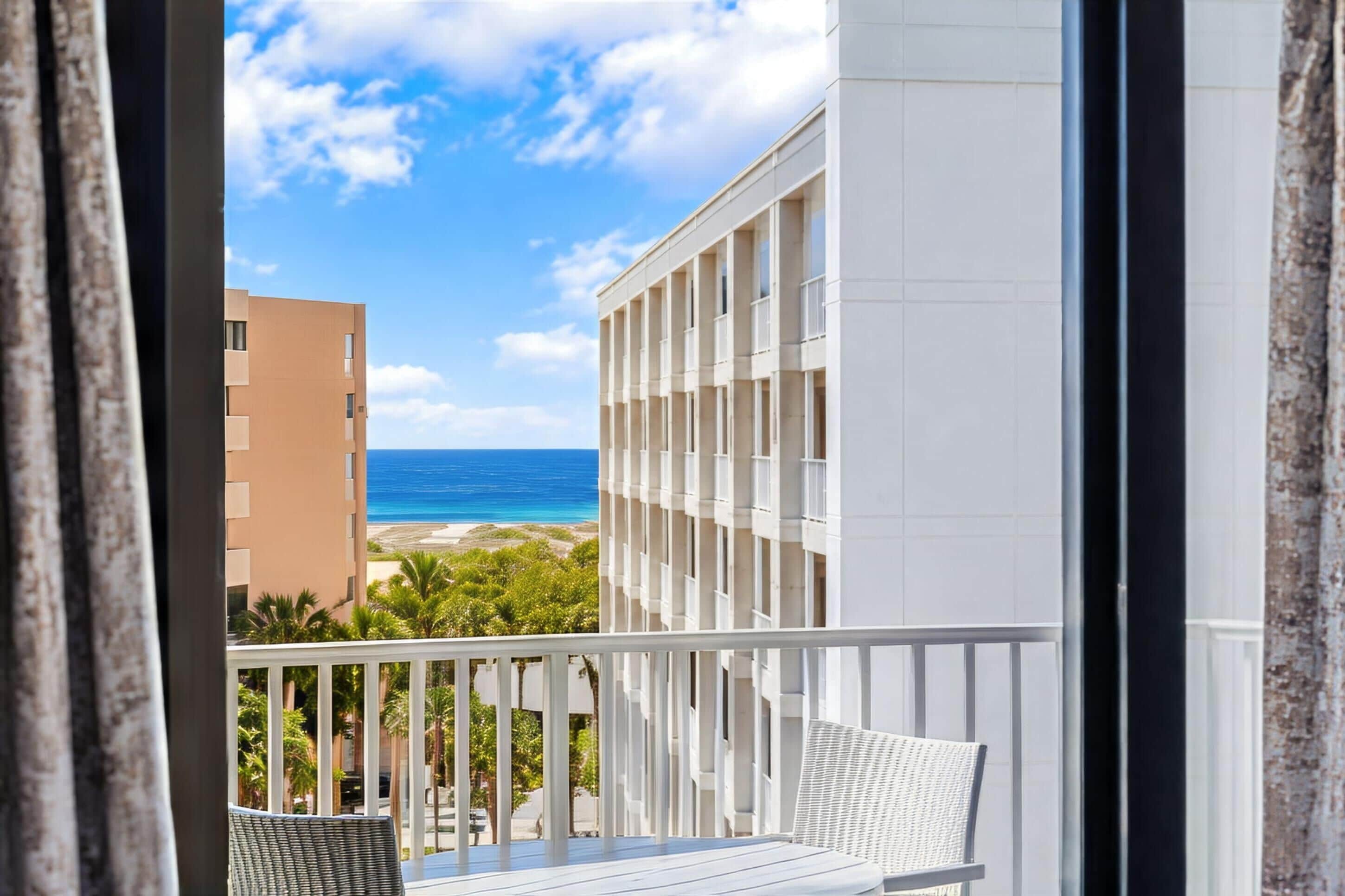 A balcony with a view of the ocean and a building with a white facade.