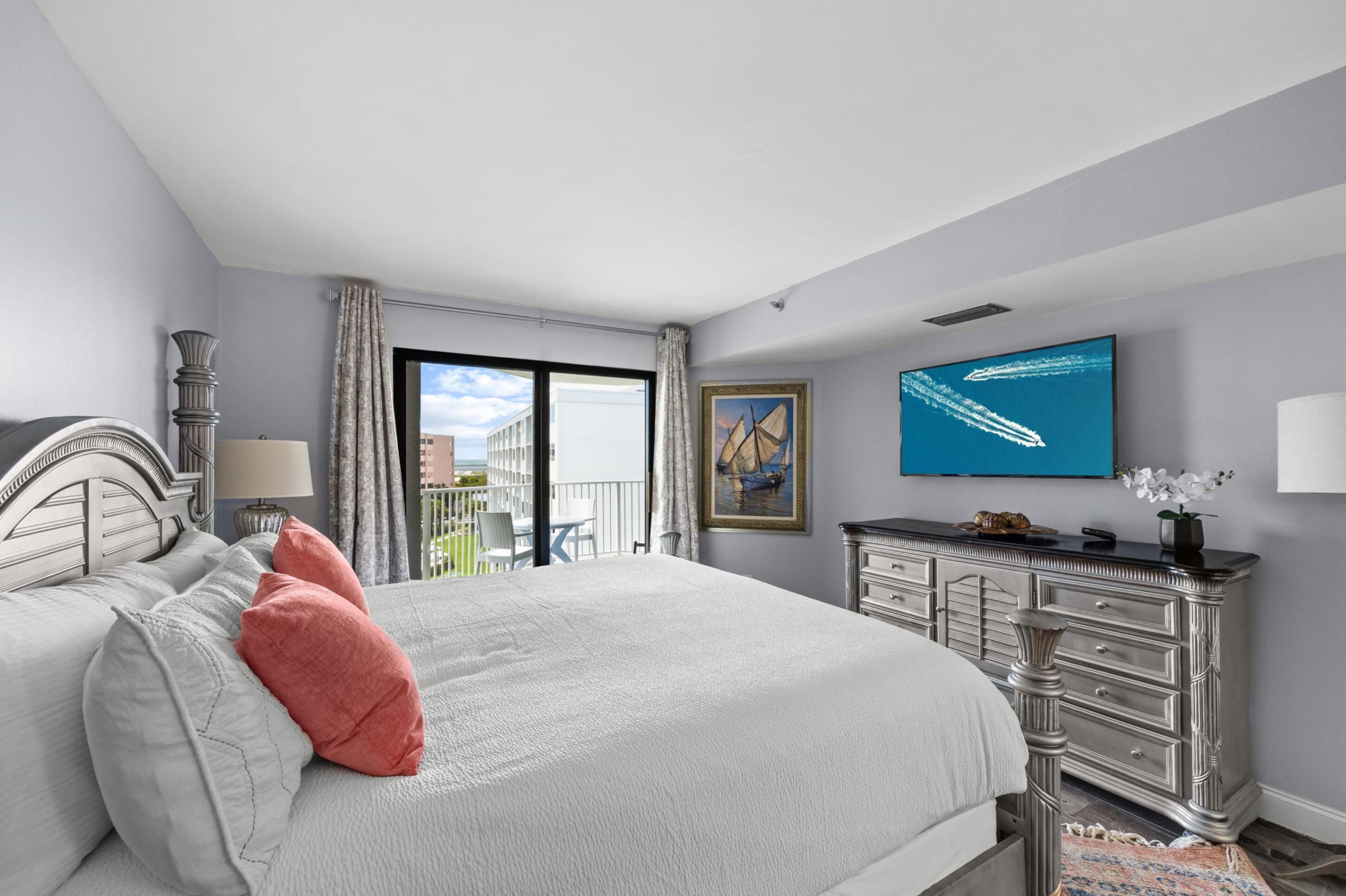 Una camera d'albergo con un letto, una cassettiera, una televisione, un quadro e vista all'esterno.