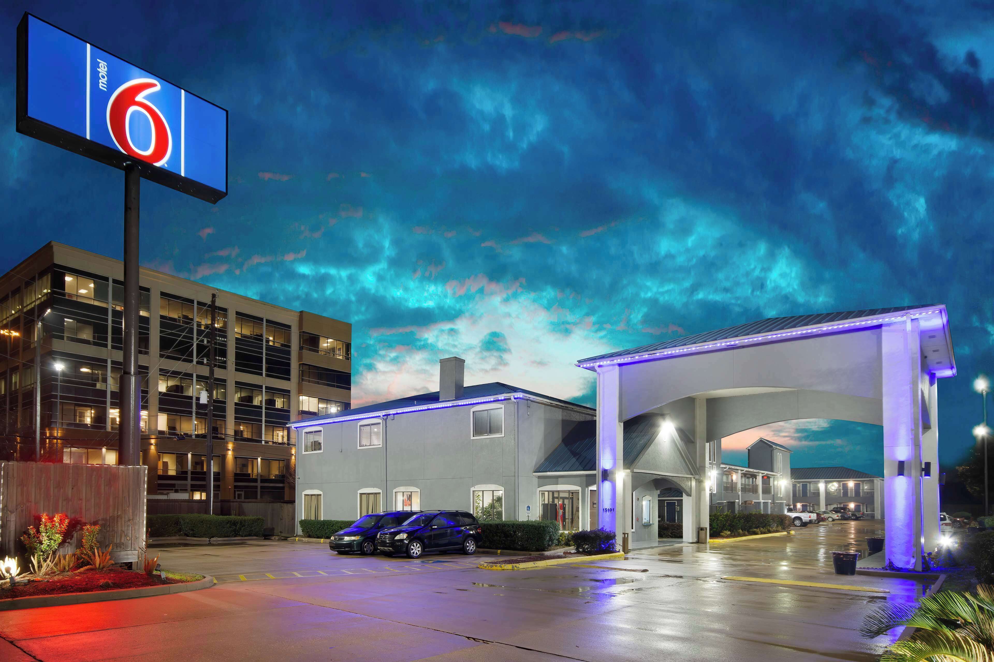 Un motel con un cartel grande, un estacionamiento y un edificio con varias ventanas.