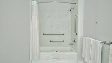 A modern bathroom with a walk-in shower, grab bars, and a towel rack.