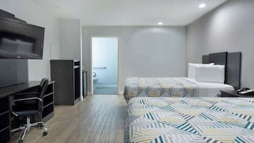 Ein Hotelzimmer mit Schreibtisch, Stuhl, zwei Betten und einem Fernseher.