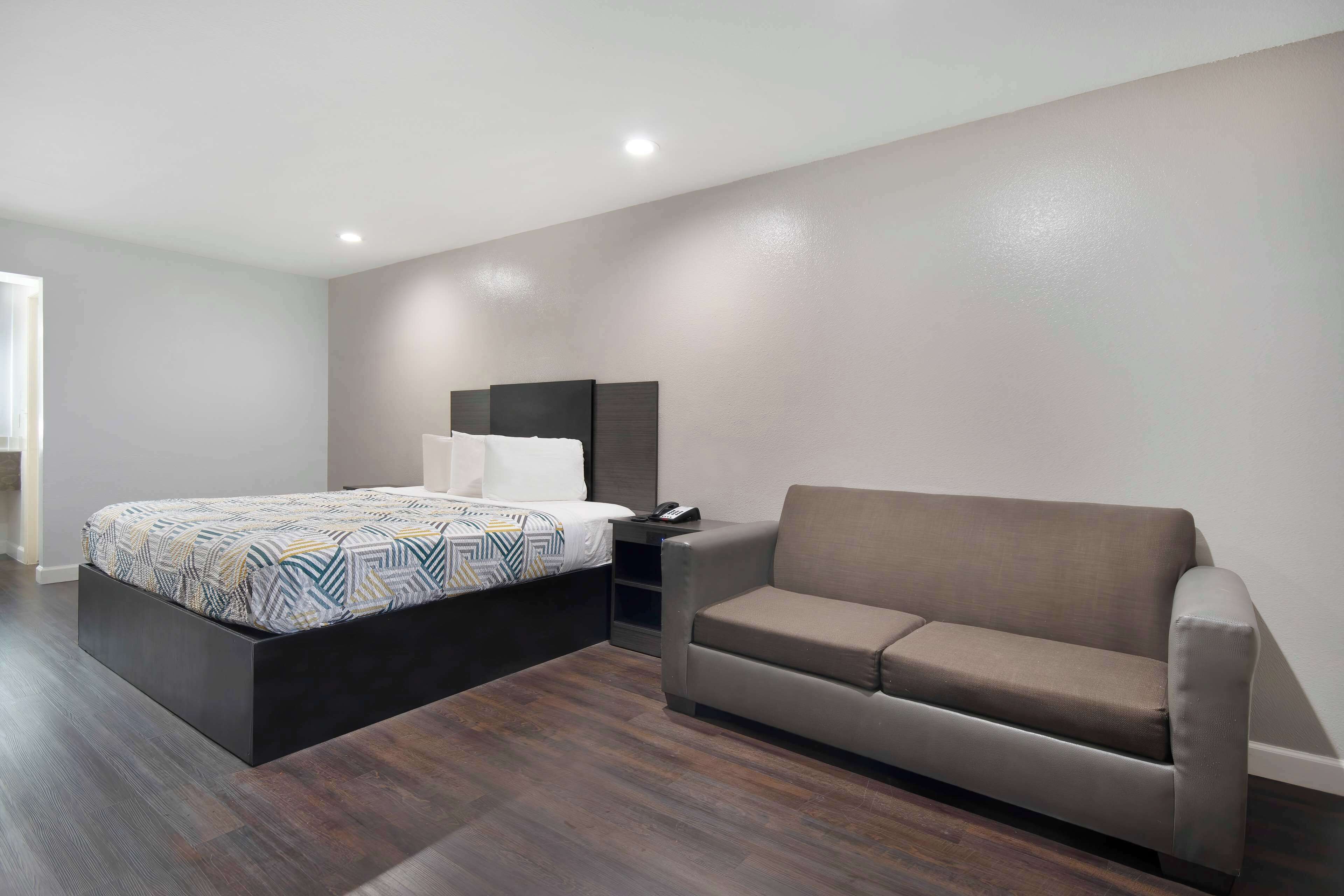 Une chambre à coucher moderne avec un lit, un canapé et une table de chevet.
