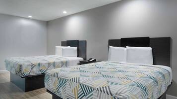 Une chambre d’hôtel avec deux lits, chacun recouvert d’une couvre-lit à motifs, une table de chevet avec un téléphone et une tête de lit moderne.