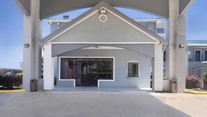 A building entrance with a covered walkway, large windows, and a visible trash bin. - Motel 6 Houston, TX - I-10 West (Houston)