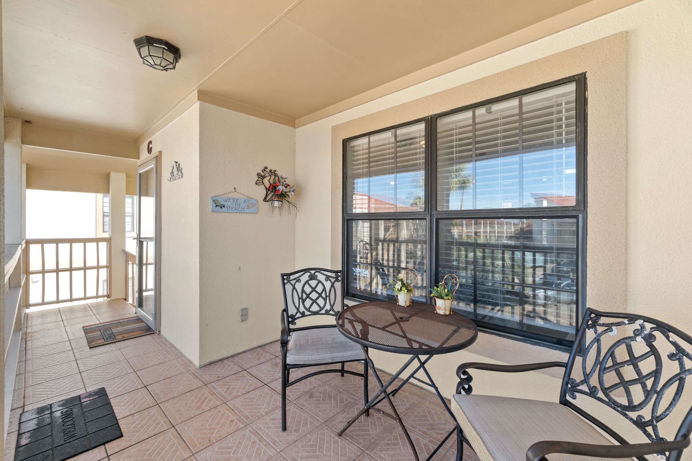 A balcony with a table and chairs, a view of the city, and a sign that says "Welcome at Beach."