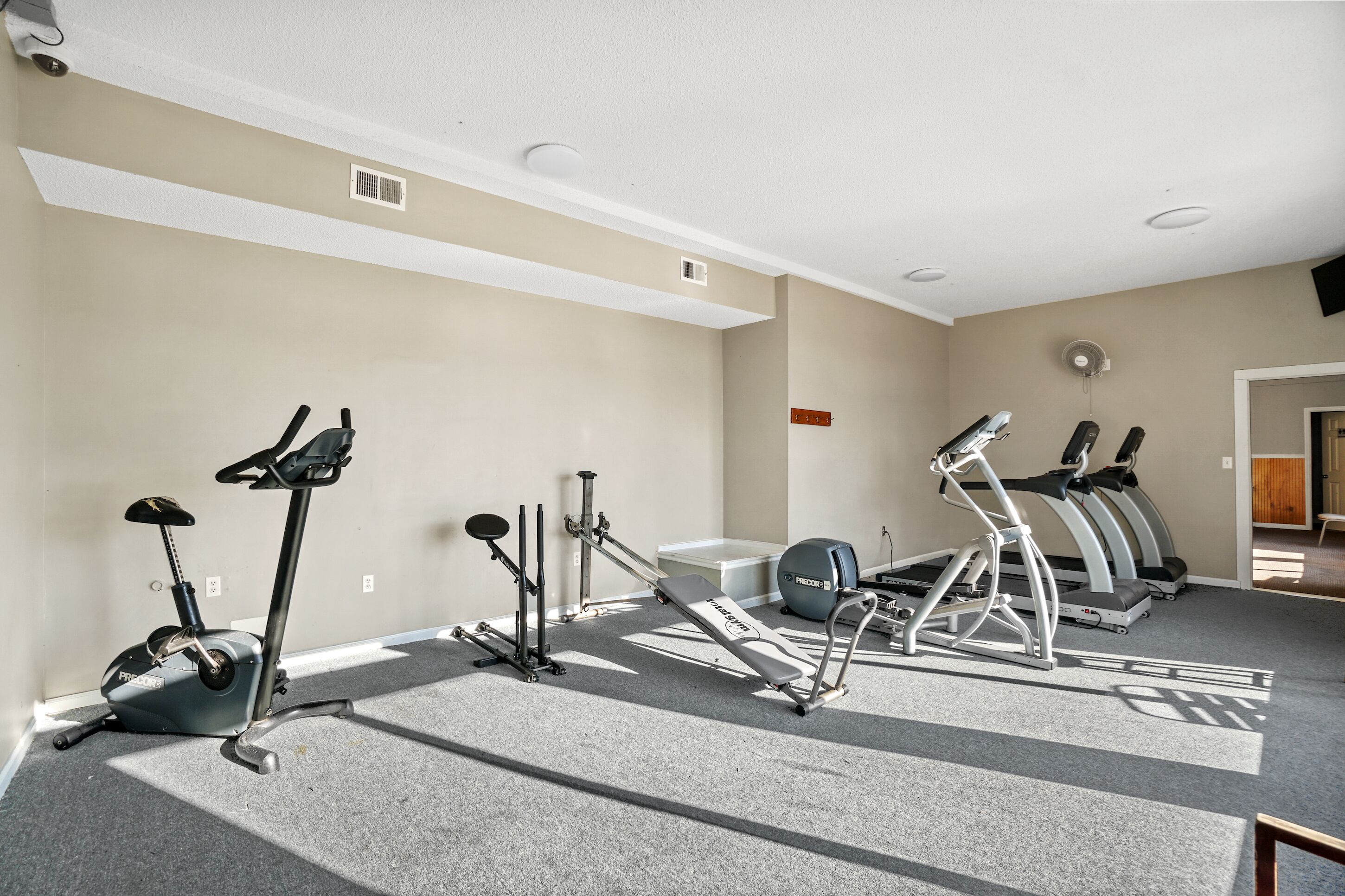 A gym with various exercise equipment including a stationary bike, elliptical, and treadmills.