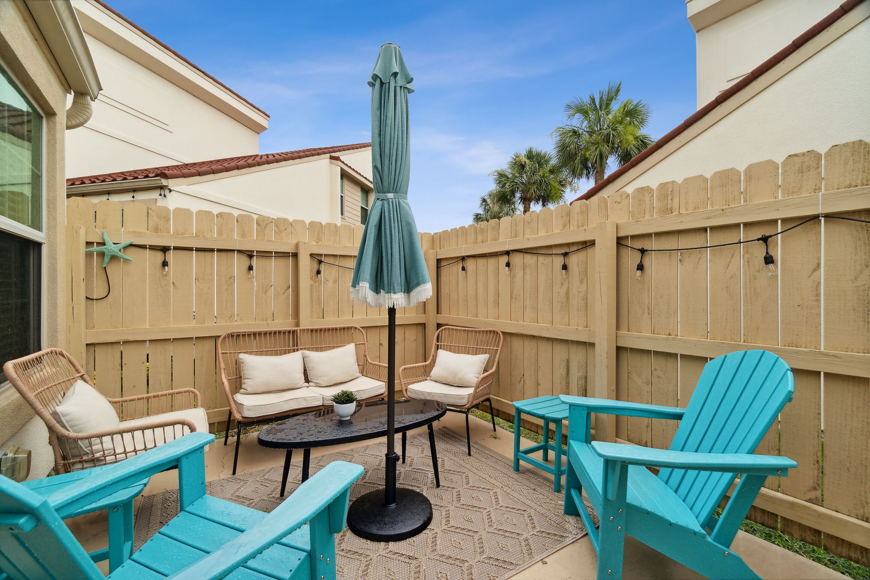 A patio with a round table, four chairs, and a single umbrella.