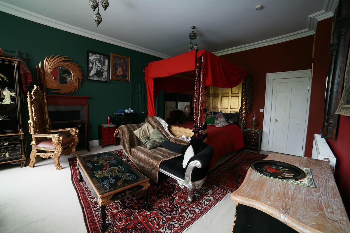 A traditional room with a four-poster bed, a fireplace, and ornate furniture.