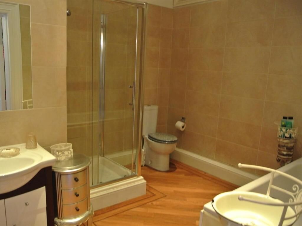 A bathroom with a glass shower enclosure, a toilet, and a sink with a mirror.