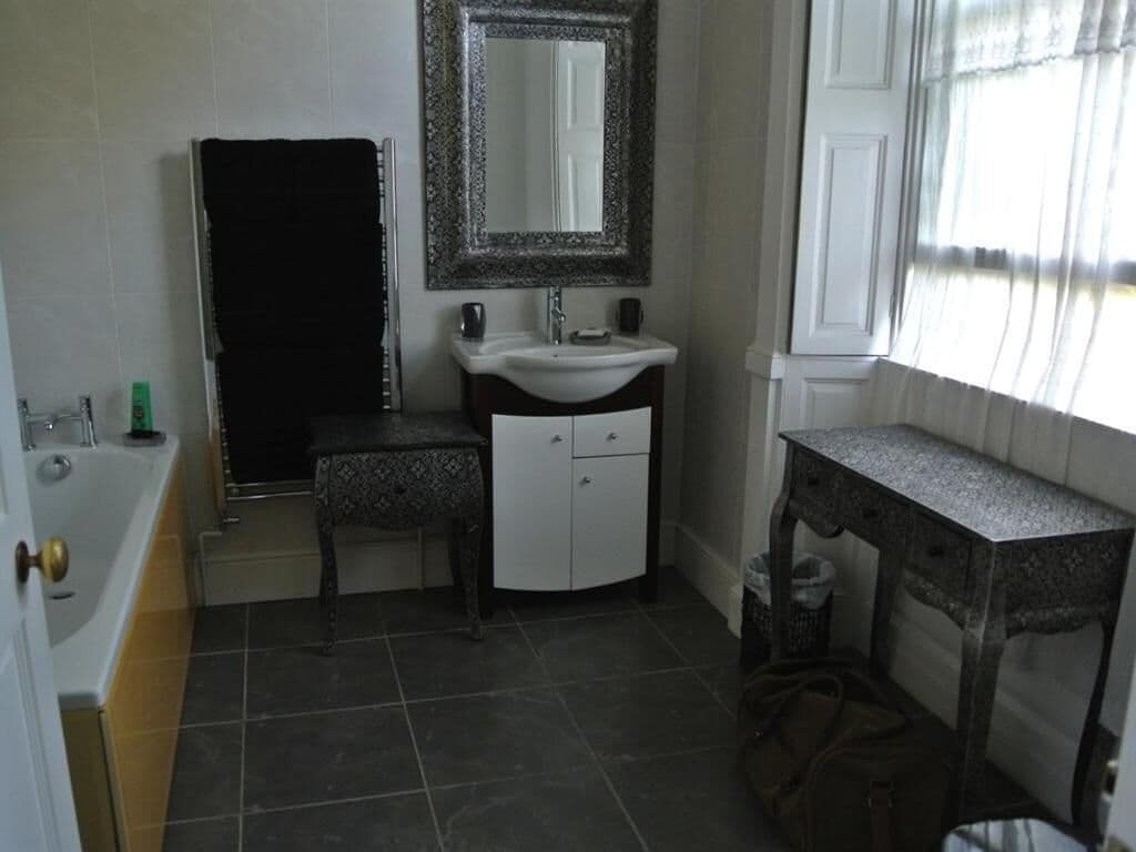 Un baño con bañera, lavamanos, tocador y espejo.