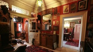 A traditional room with a large wooden cabinet, a red patterned rug, and a television. - The Covenstead (Glastonbury)