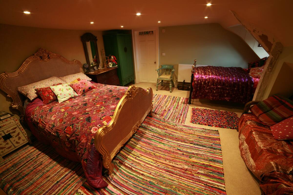 A bedroom with a large bed, a smaller bed, a chair, and a dresser.