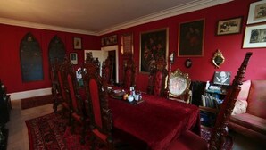 A dining room with a red carpet, wooden chairs, and a table set for dining. - The Covenstead (Glastonbury)