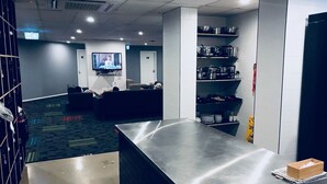 A modern kitchen with stainless steel countertops, a flat-screen TV mounted on the wall, and a seating area with sofas. - Down Under Hostels - Surfers Paradise (Surfers Paradise)