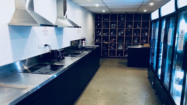 A modern kitchen with stainless steel appliances, a large range hood, and a refrigerator with glass doors. - Down Under Hostels - Surfers Paradise (Surfers Paradise)