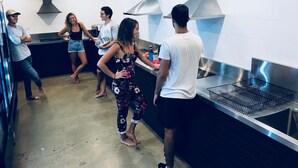 A modern kitchen with stainless steel appliances, a large island, and a high ceiling. - Down Under Hostels - Surfers Paradise (Surfers Paradise)