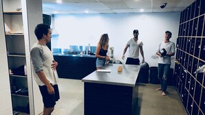 A group of people in a modern kitchen with a central island, built-in shelves, and a wall of storage lockers. - Down Under Hostels - Surfers Paradise (Surfers Paradise)
