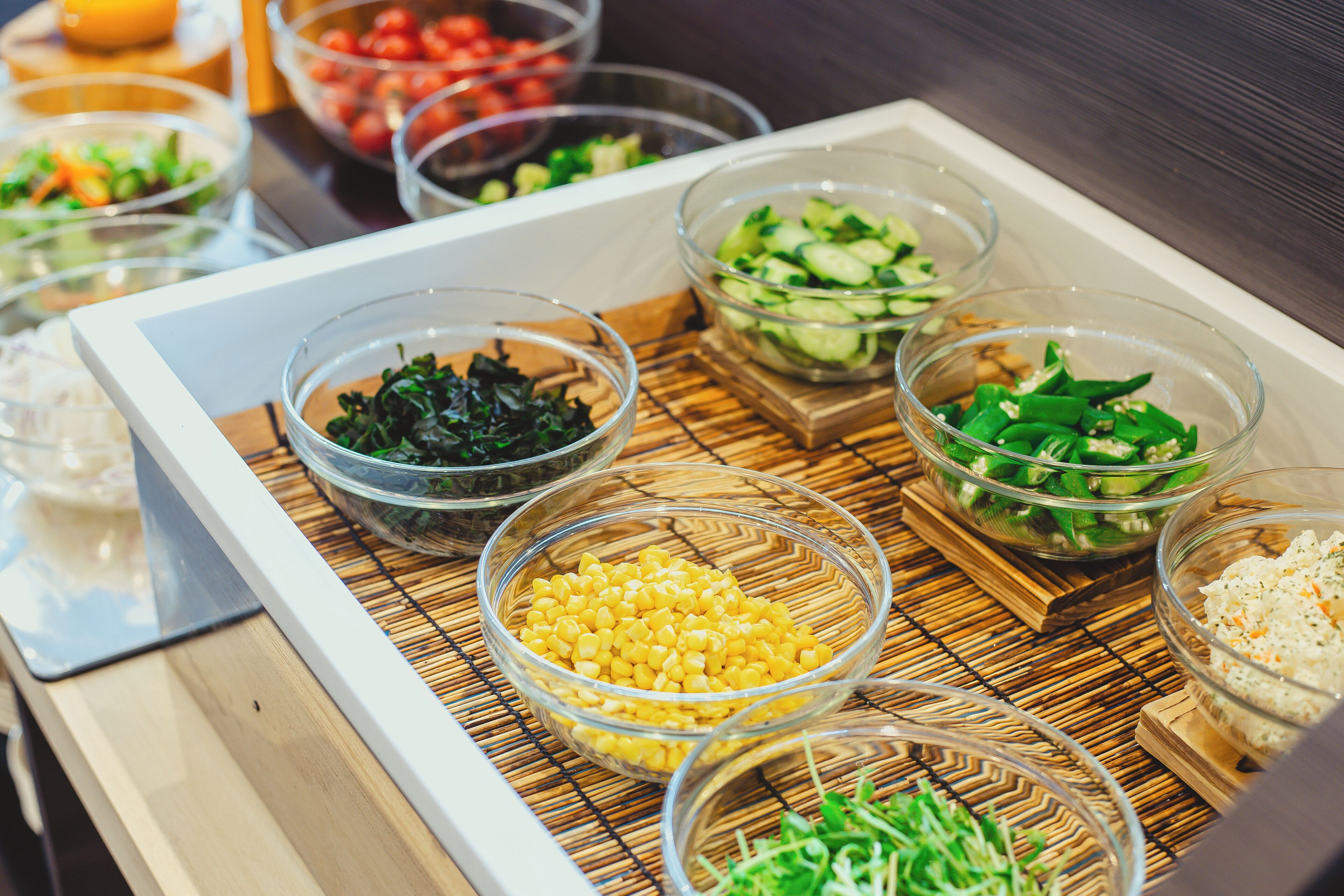 Una mesa de buffet con diversos alimentos en recipientes transparentes.