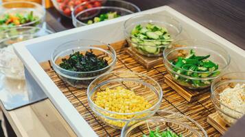Una mesa de buffet con diversos alimentos en recipientes transparentes.