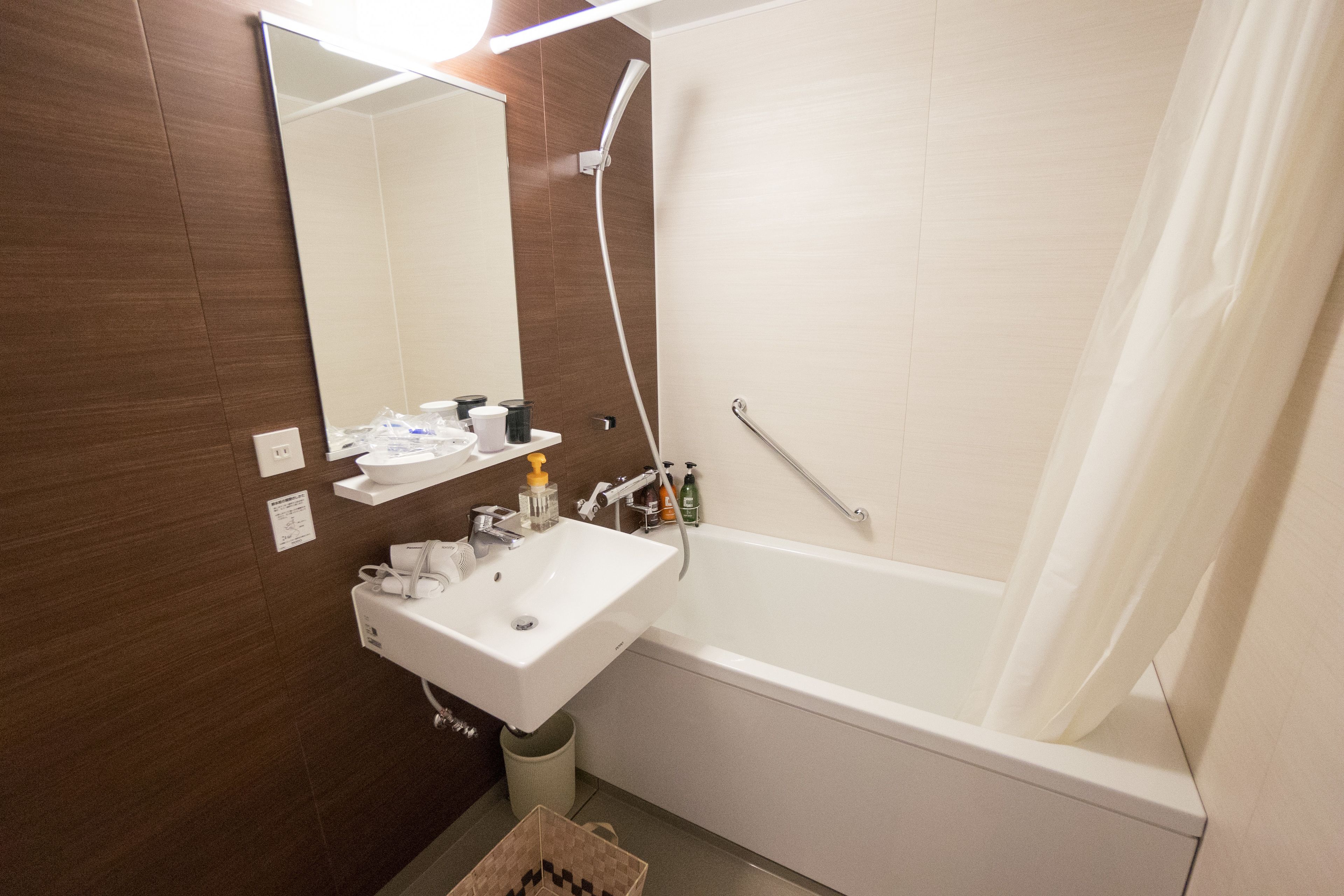 A modern bathroom with a white sink, mirror, and bathtub.