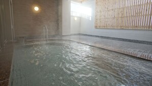 A hot tub area with a wooden ceiling, tiled floor, and a bamboo wall.