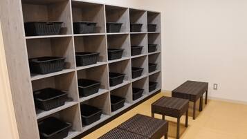 A room with a large shelving unit filled with black baskets, a clock on the wall, and three wicker tables.