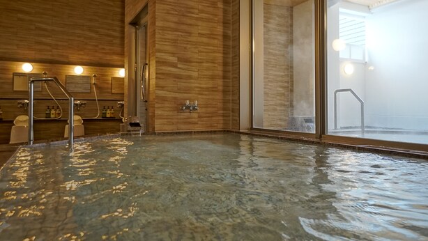 A spa area with a hot tub, wooden walls, and a glass door leading outside.