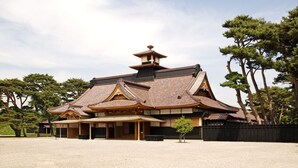 A traditional Japanese building with a tiled roof, wooden structure, and a small pagoda-like structure on top.