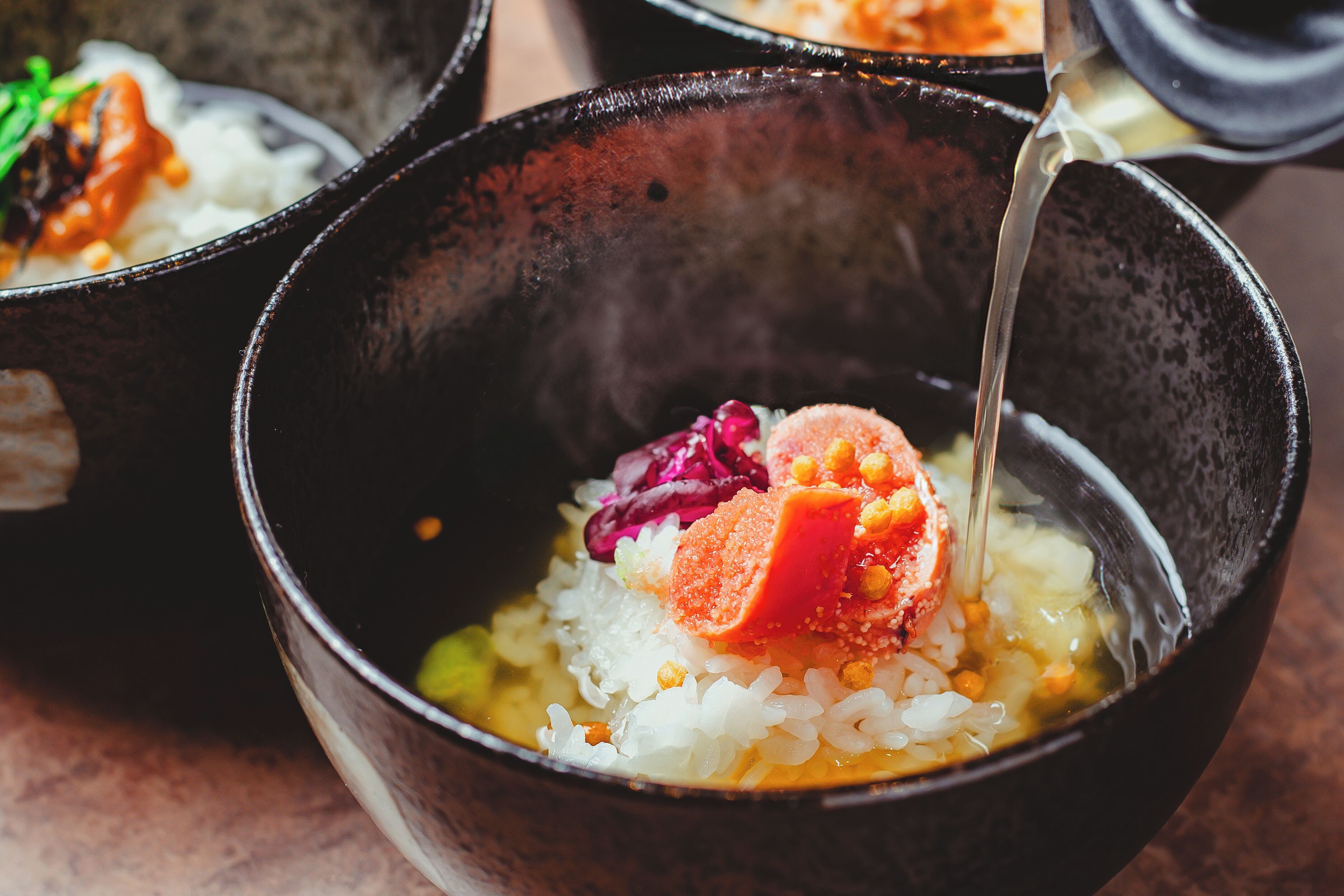 A bowl of rice with a piece of salmon and other ingredients.