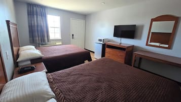 Una habitación de hotel con dos camas, televisión, escritorio y ventana con cortinas.