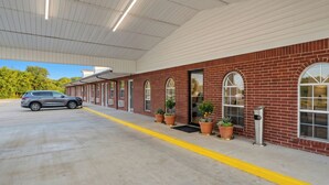 A building with a brick facade, large windows, and a covered parking area.