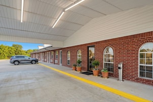 A building with a brick facade, large windows, and a covered parking area.