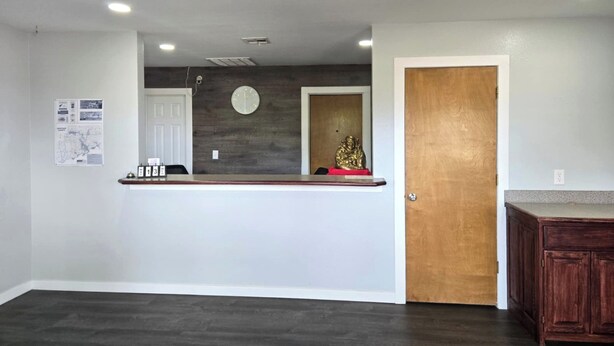 A reception area with a counter, a clock, and a wooden door.