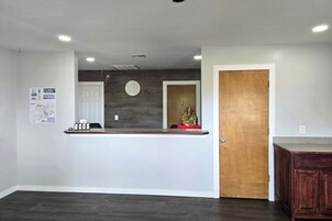 A reception area with a counter, a clock, and a wooden door.