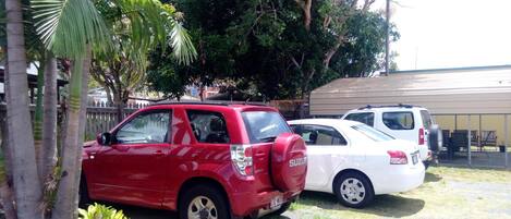 A red SUV and a white car parked in a lot with a building in the background.