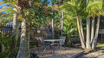 A patio area with a table and chairs, surrounded by palm trees and tropical plants.