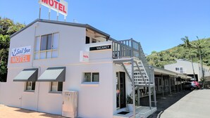 Un motel con un letrero de 'Vacancy', un área exterior cubierta y una escalera que conduce a un balcón.