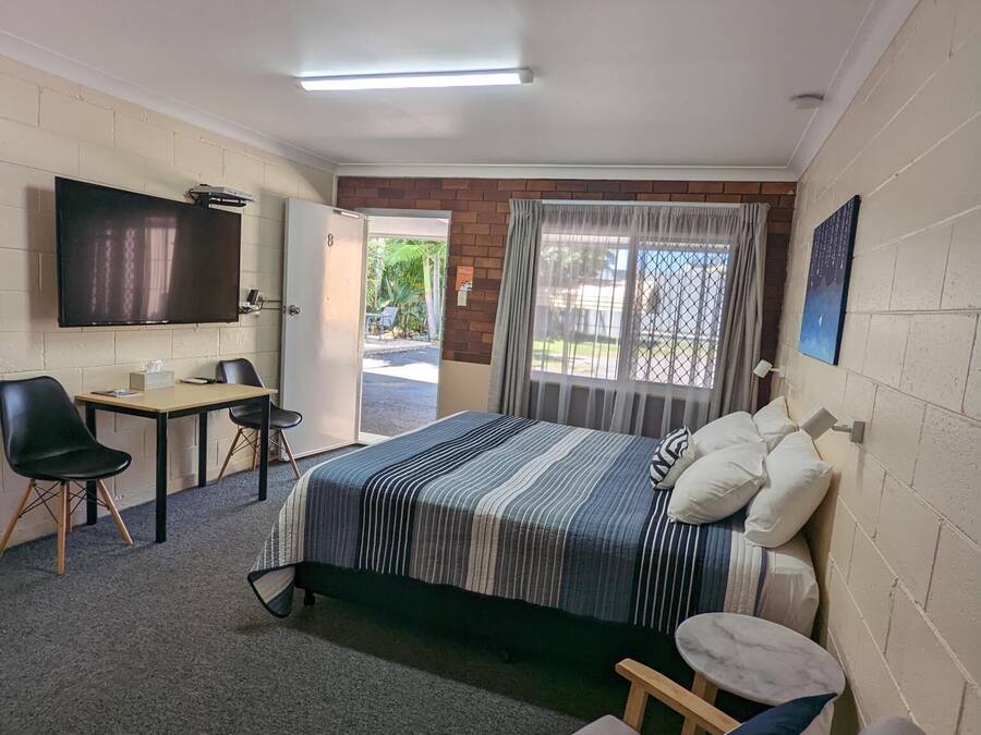 A hotel room with a bed, a desk, a chair, a television, and a window with curtains.