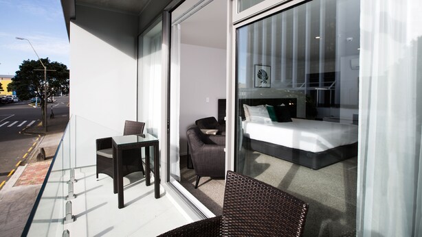 Een moderne hotelkamer met een glazen wand, een bed, een stoel en een kleine tafel.