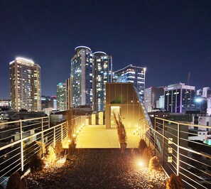 A nighttime cityscape with modern high-rise buildings and a well-lit pedestrian bridge. - Yolo Guesthouse - Hostel (Seoul)