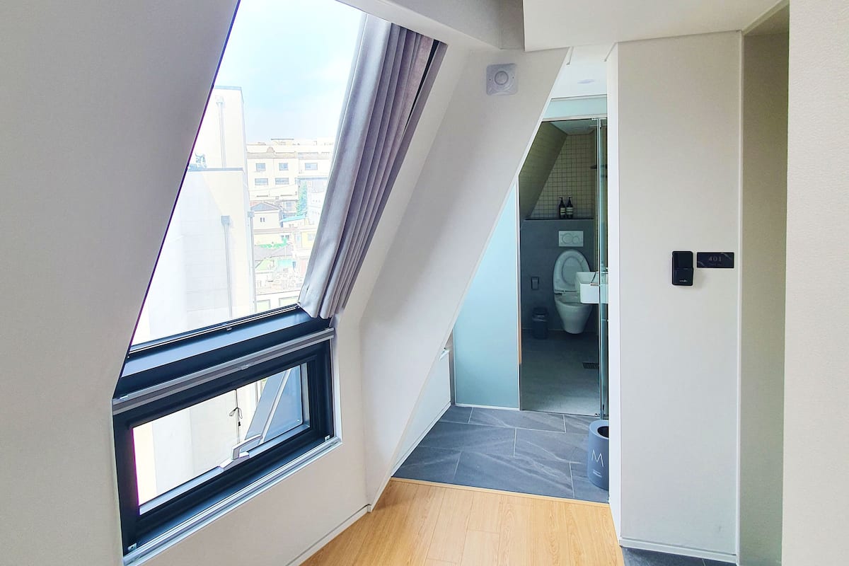 Una habitación moderna con techo inclinado, tragaluz y vista panorámica de la ciudad.
