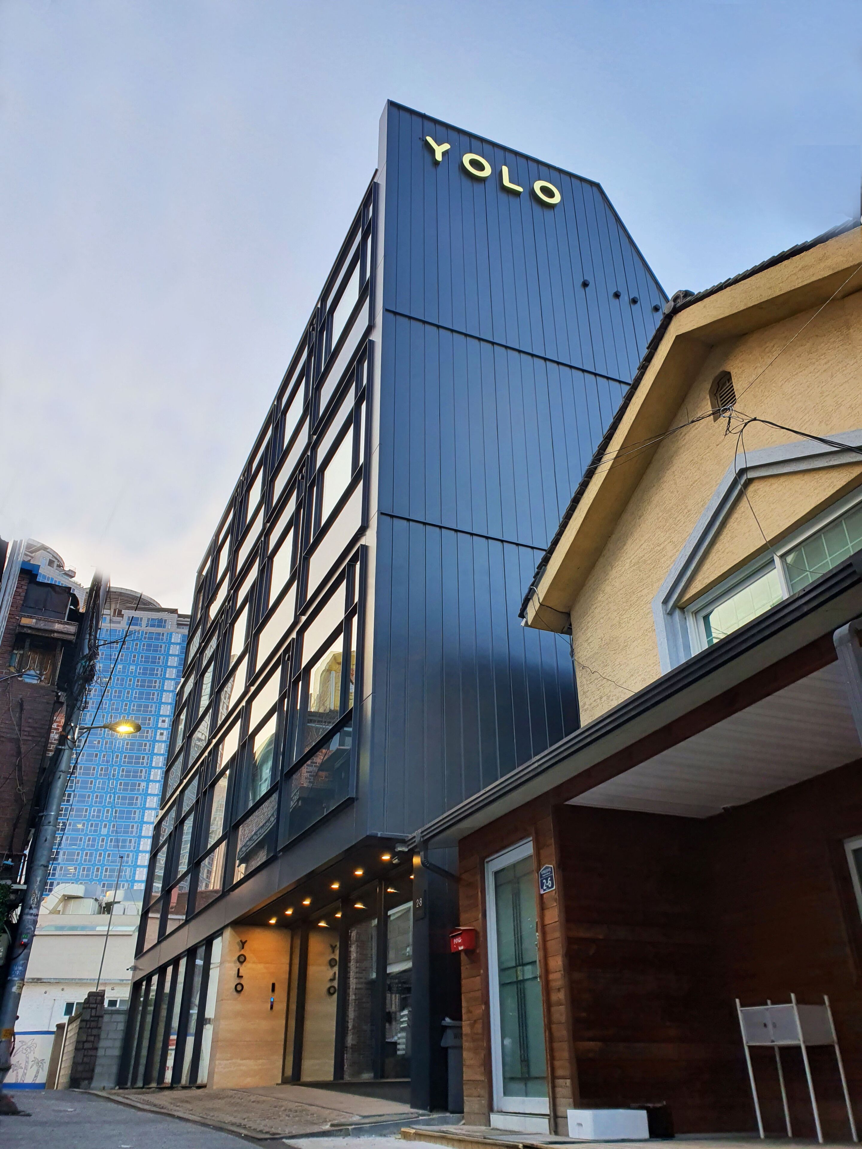 A modern building with a prominent 'YOLO' sign on the facade, featuring a mix of glass and metal construction.
