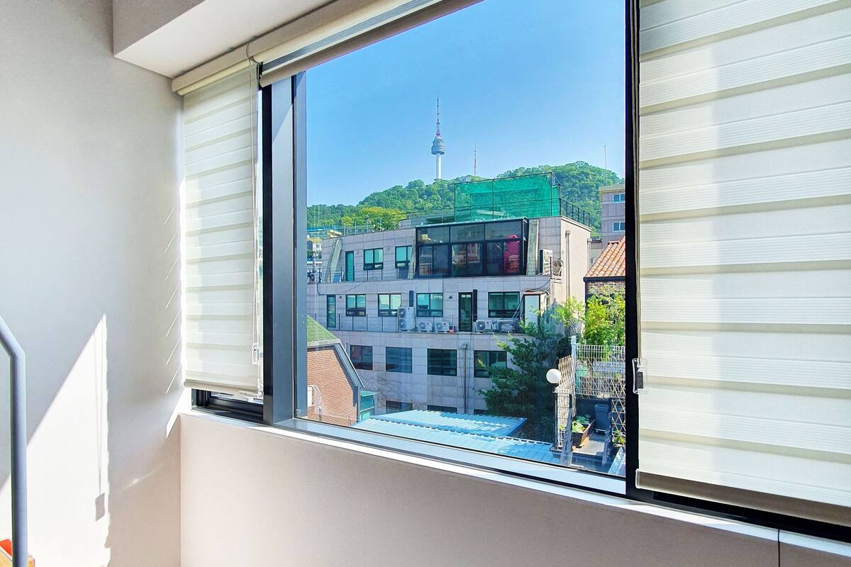 Una habitación con un gran ventanal, una escalera y vistas a edificios y una torre.